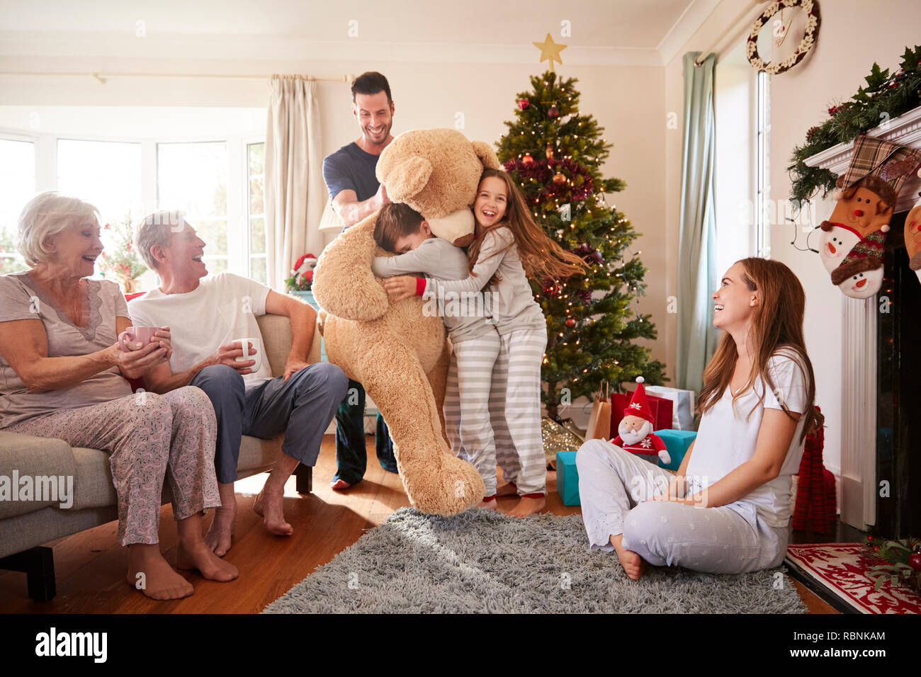 Kinder spielen mit riesigen Teddybär als Multi-Generation Familie Geschenke an Weihnachten Stockfoto