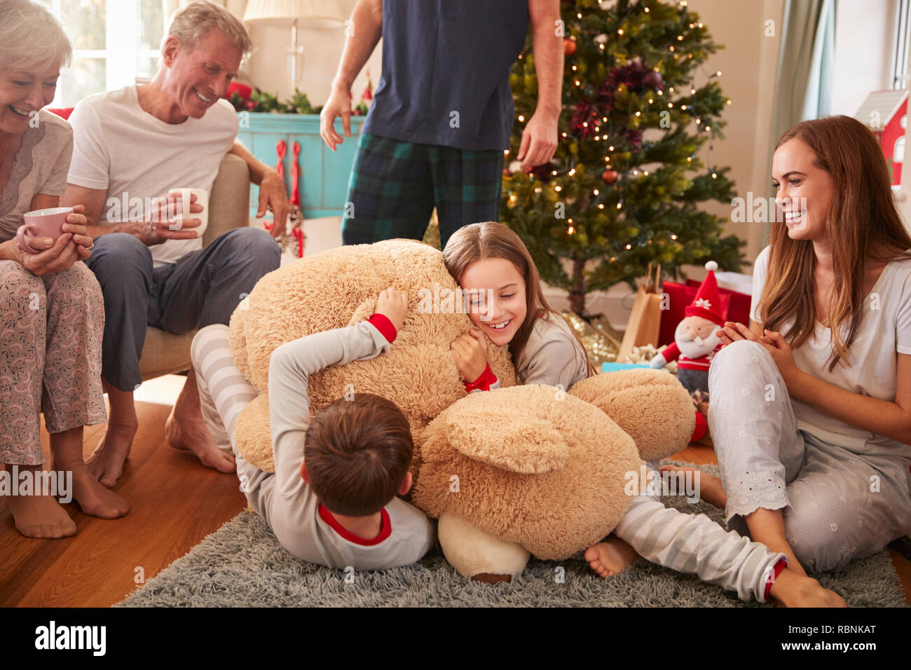 Kinder spielen mit riesigen Teddybär als Multi-Generation Familie Geschenke an Weihnachten Stockfoto