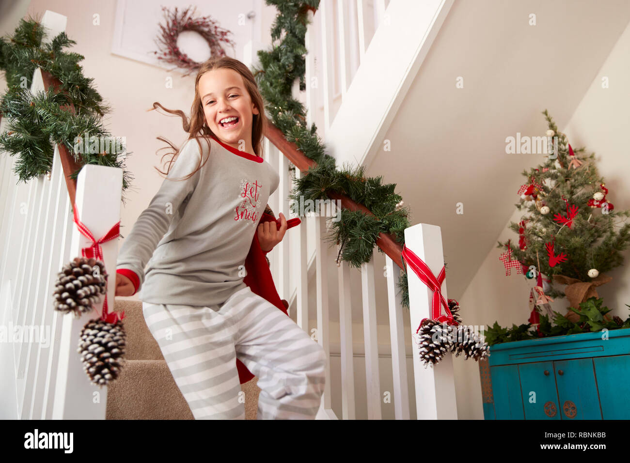 Aufgeregt Mädchen mit Schlafanzug laufen die Treppe Holding Strumpf am Weihnachtsmorgen Stockfoto