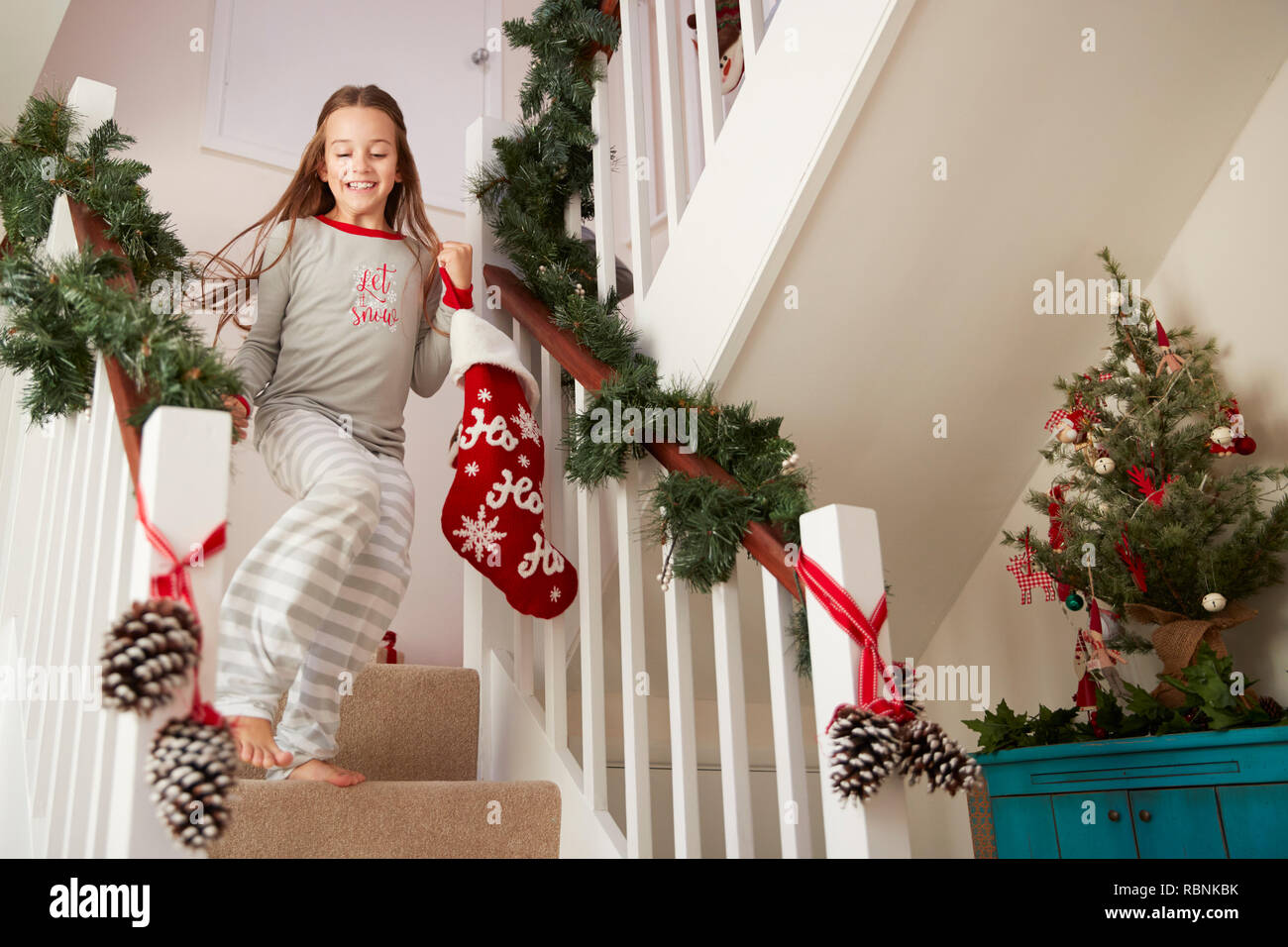 Aufgeregt Mädchen mit Schlafanzug laufen die Treppe Holding Strümpfe am Weihnachtsmorgen Stockfoto