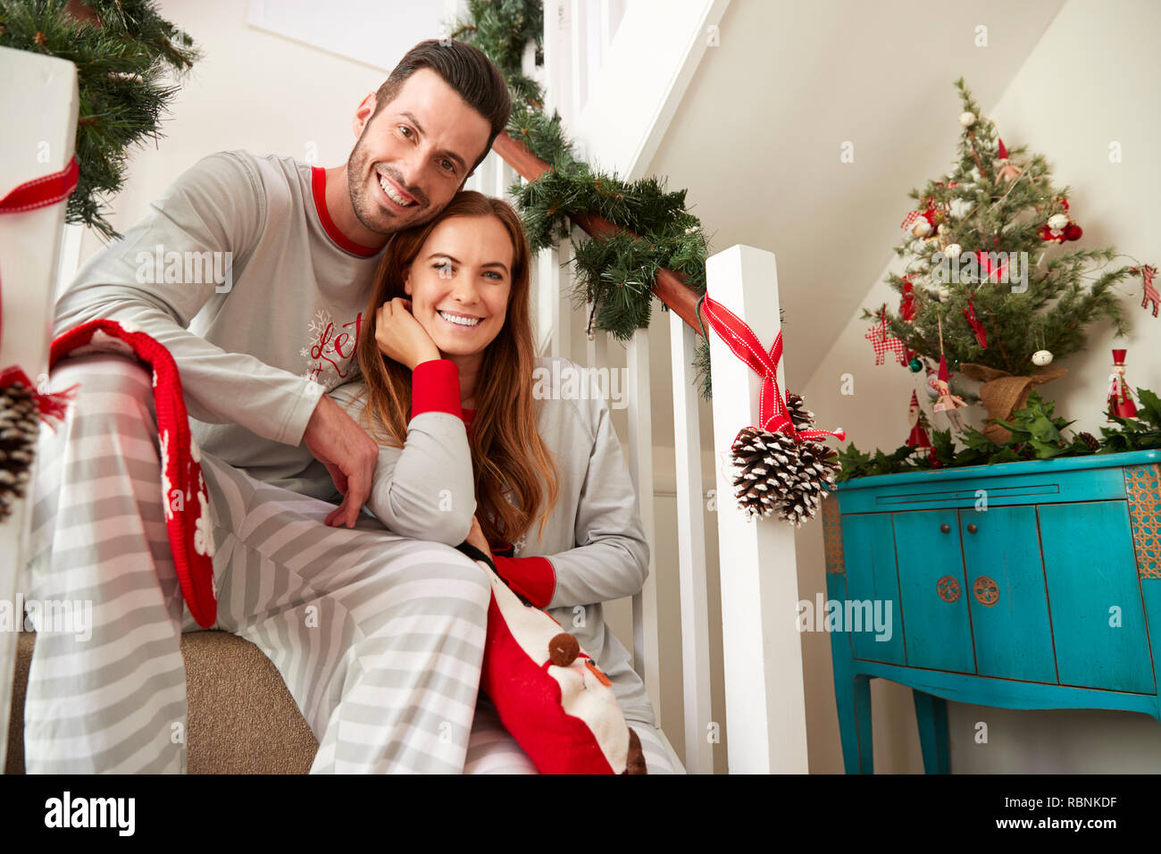 Portrait von Paar Tragen Schlafanzug Sitzen auf der Treppe am Weihnachtsmorgen Stockfoto