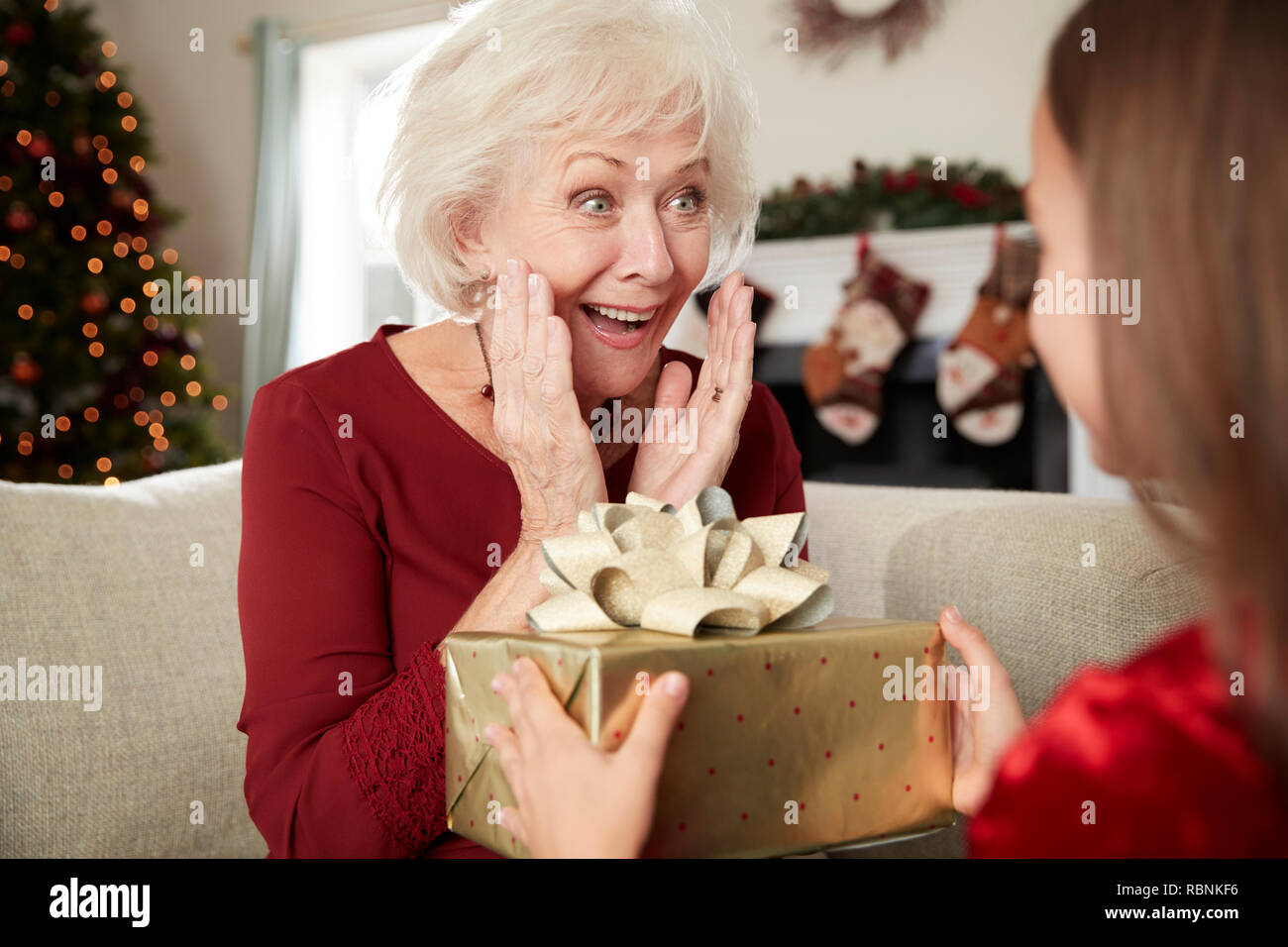 Aufgeregt Großmutter empfangen Weihnachtsgeschenk von Enkelin zu Hause Stockfoto