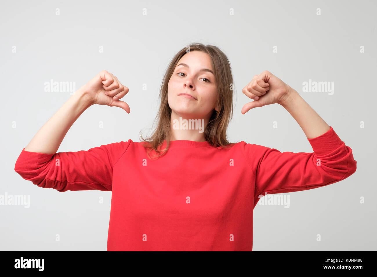 Junge hübsche Frau in Rot Pullover stolz und selbstbewusst, Pointing Finger, Beispiel zu folgen. Konzept der egoistisch und egozentrisch Person Stockfoto
