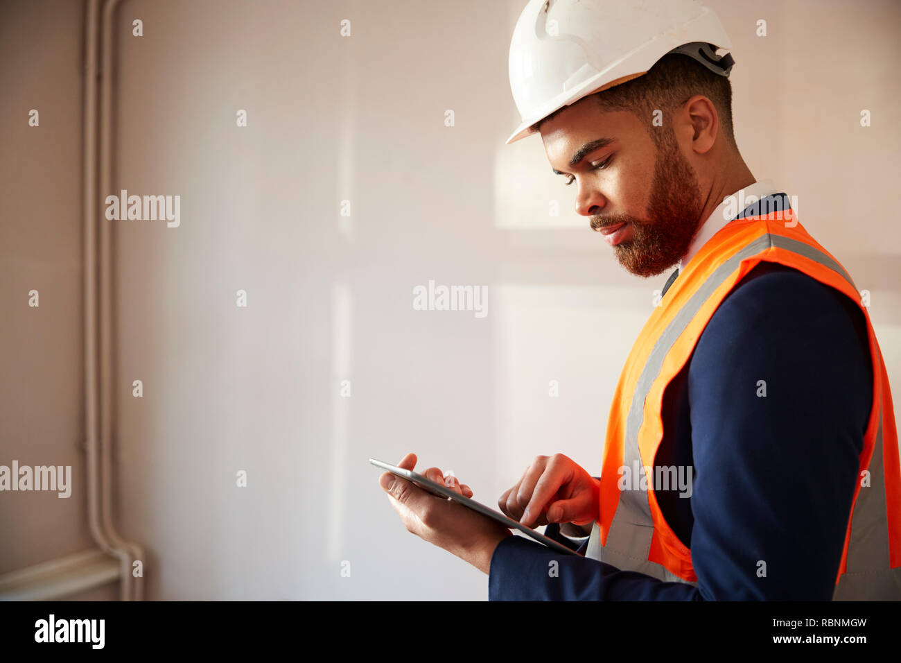 Surveyor in harten Hut und hohe Sichtbarkeit Jacke mit digitalen Tablet Durchführung eigener Prüfung Stockfoto