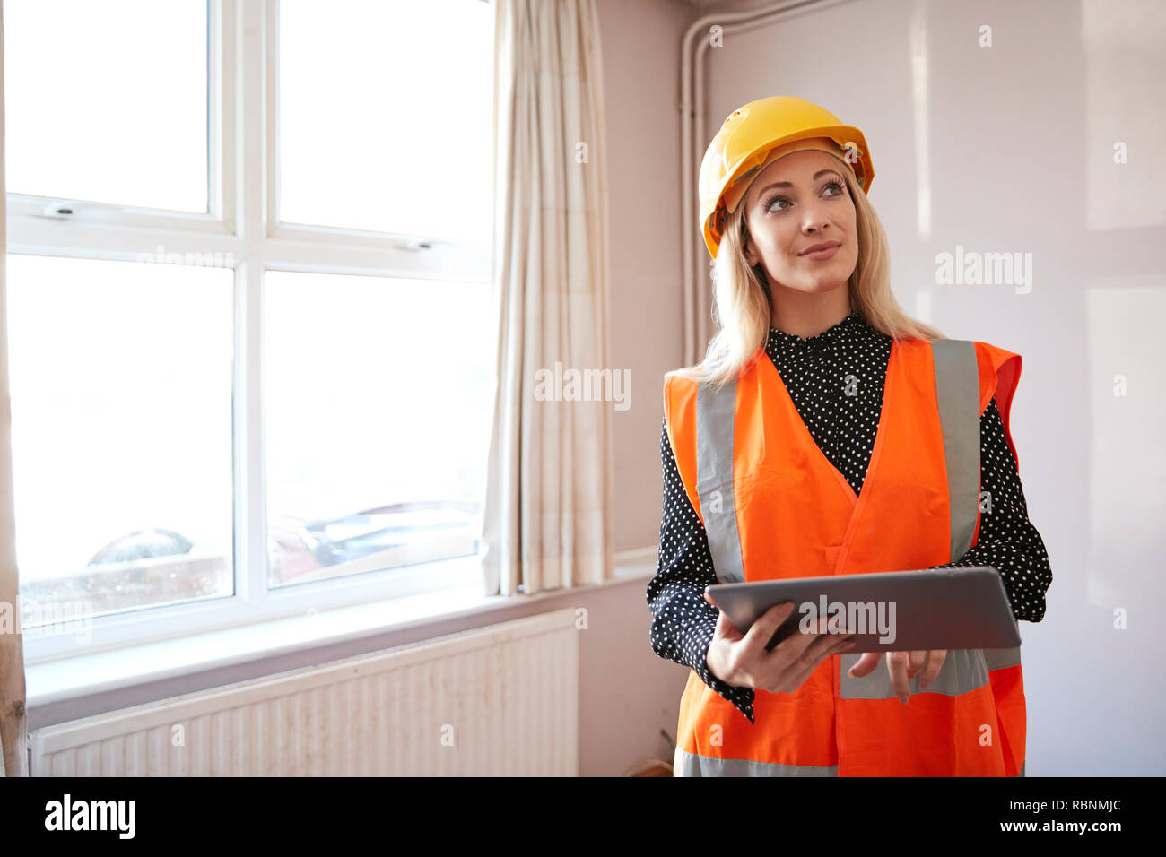 Weibliche Surveyor in harten Hut und hohe Sichtbarkeit Jacke mit digitalen Tablet Durchführung eigener Prüfung Stockfoto
