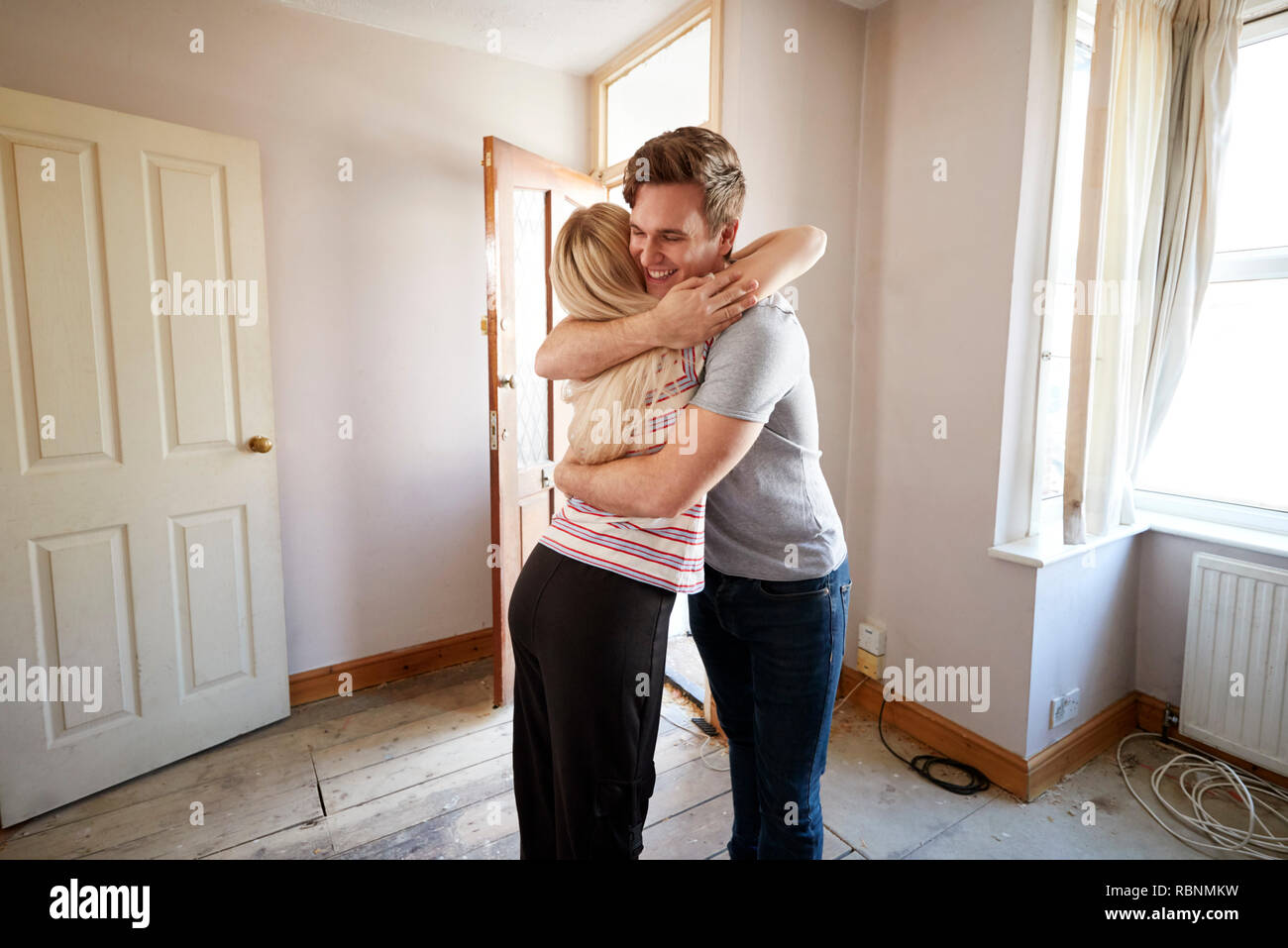 Junges Paar umarmen durch die vordere Tür des Neuen begeistern Stockfoto
