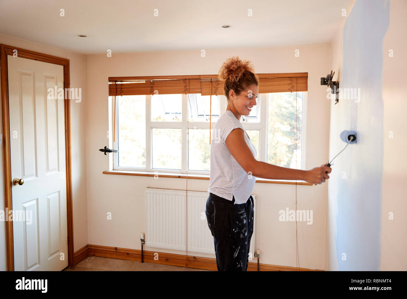 Frau dekorieren Zimmer im neuen Haus Malerei Wand Stockfoto