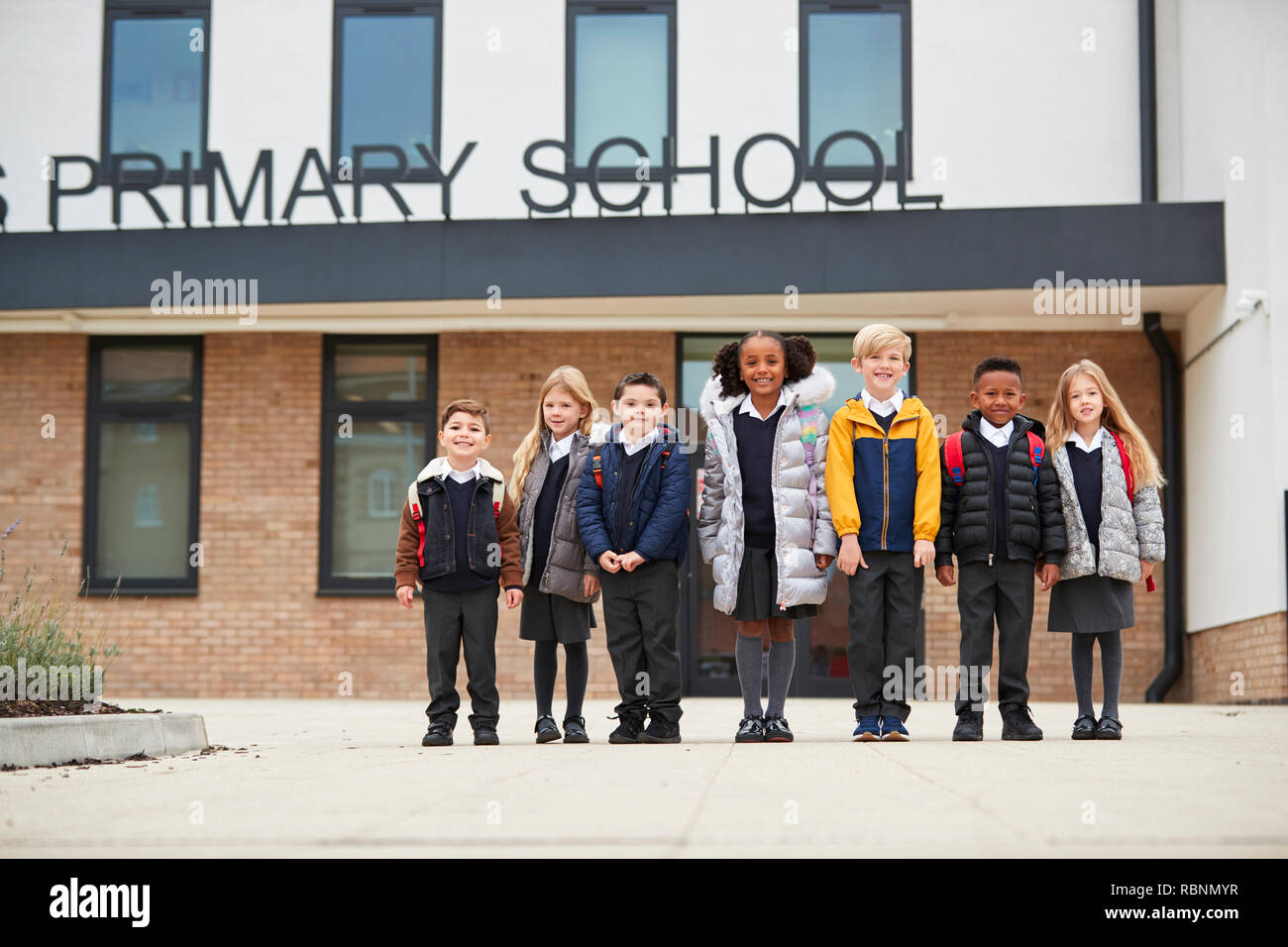 Grundschule Kinder stehen vor Ihrer Schule zu Kamera suchen, volle Länge, niedrigen Winkel Stockfoto