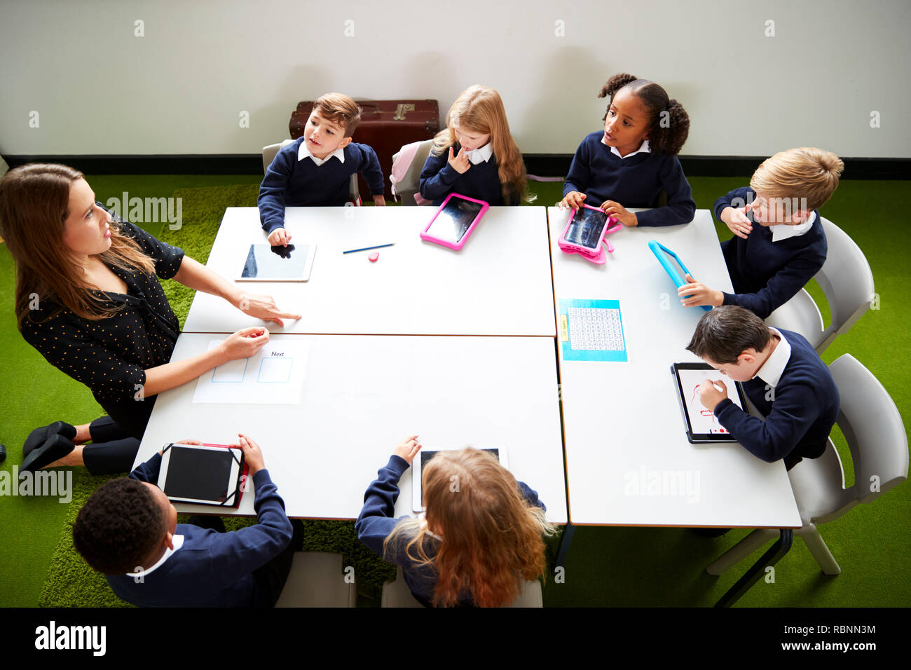 Ansicht der Grundschule Kinder sitzen um einen Tisch in der Klasse mit ihrer Lehrerin Stockfoto