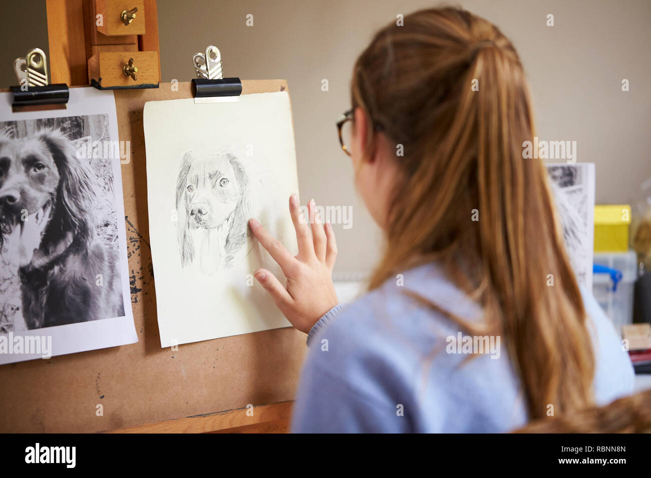 Ansicht der Rückseite des weiblichen Teenager Künstler sitzen an Staffelei Zeichnung Bild von Hund von Foto in Anthrazit Stockfoto