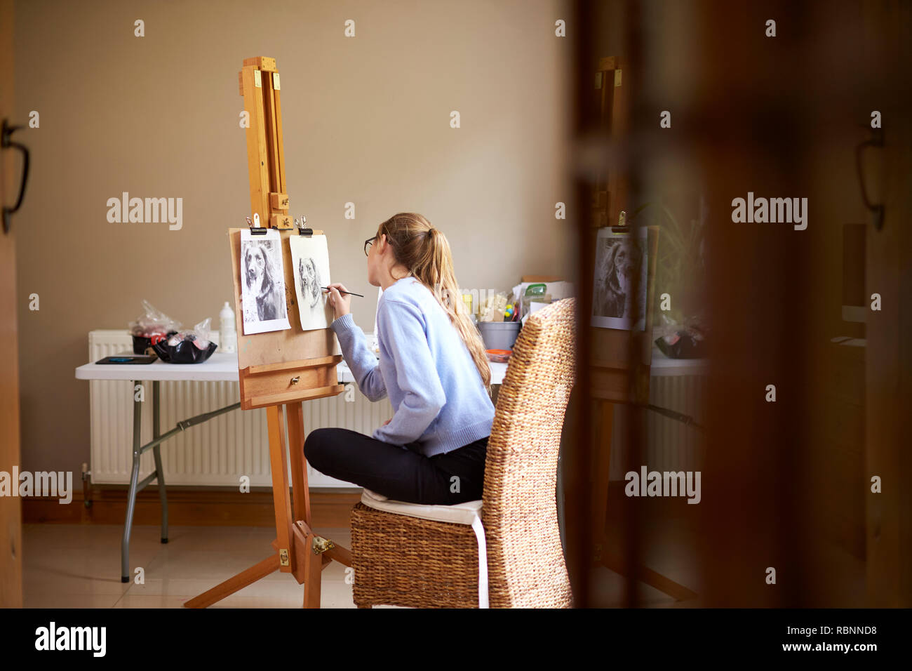 Seitenansicht der weiblichen Teenager Künstler sitzen an Staffelei Zeichnung Bild von Hund von Foto in Anthrazit Stockfoto