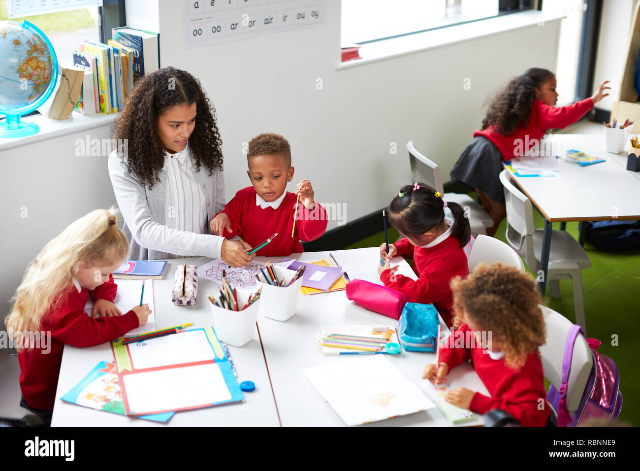 Ansicht der weiblichen Kindergärtnerin sitzen an einem Tisch, vier Kinder während einer Lektion Stockfoto