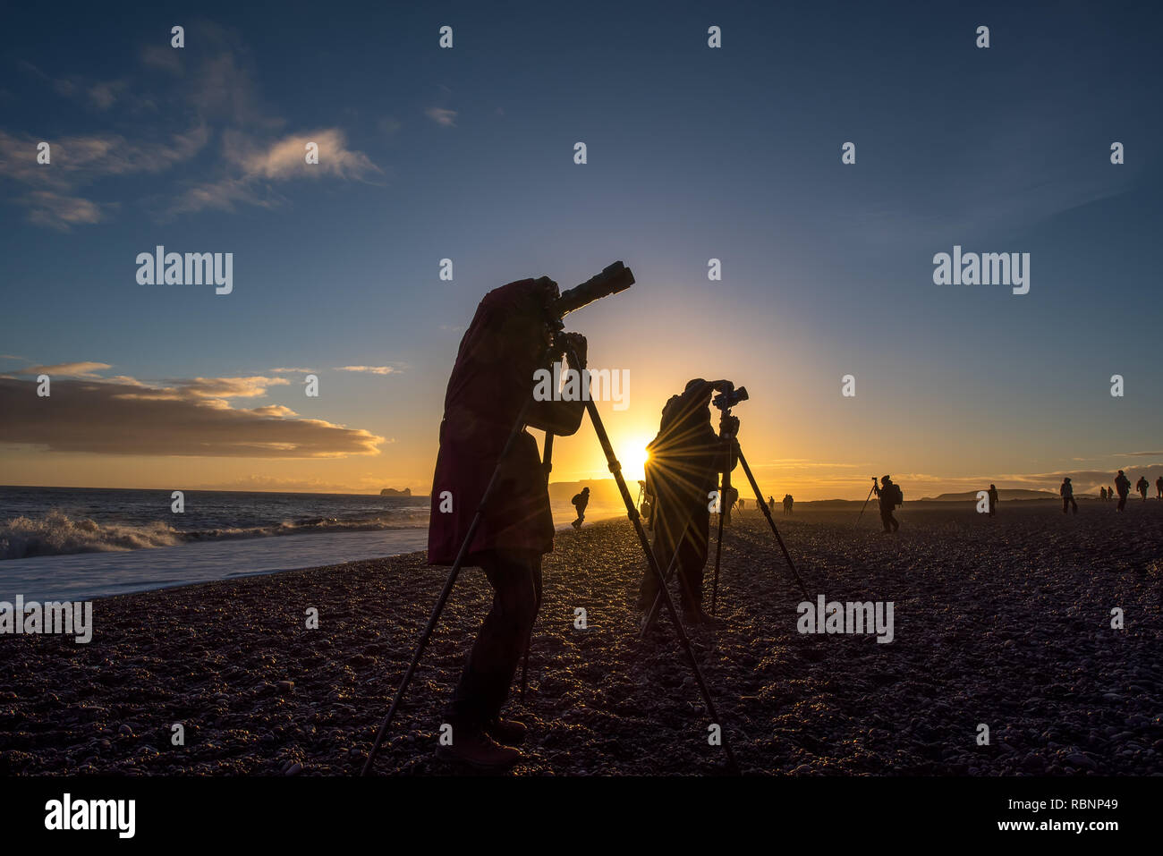 Silhouetten von Fotografen am Strand bei Sonnenuntergang im goldenen Licht Stockfoto