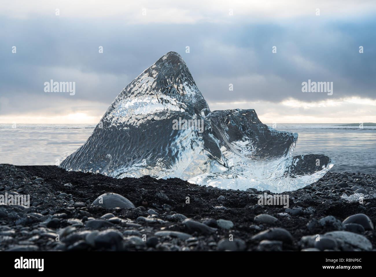 Transparente Eisberg auf steinigem Strand Stockfoto