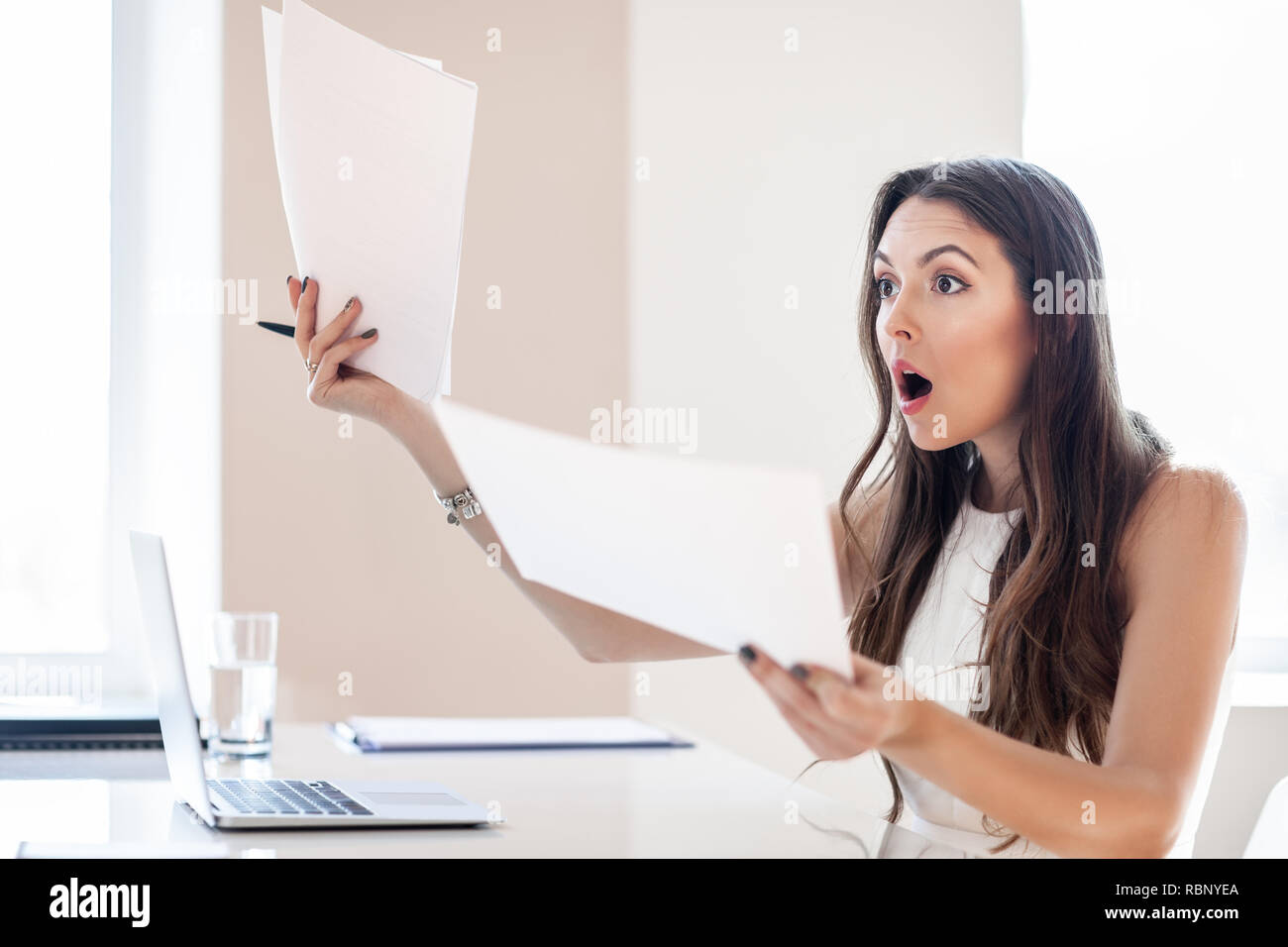 Entsetzte Geschäftsfrau lesen Papier am Arbeitsplatz im Büro. Business woman frustriert und mit neuen Vertrag betont Stockfoto