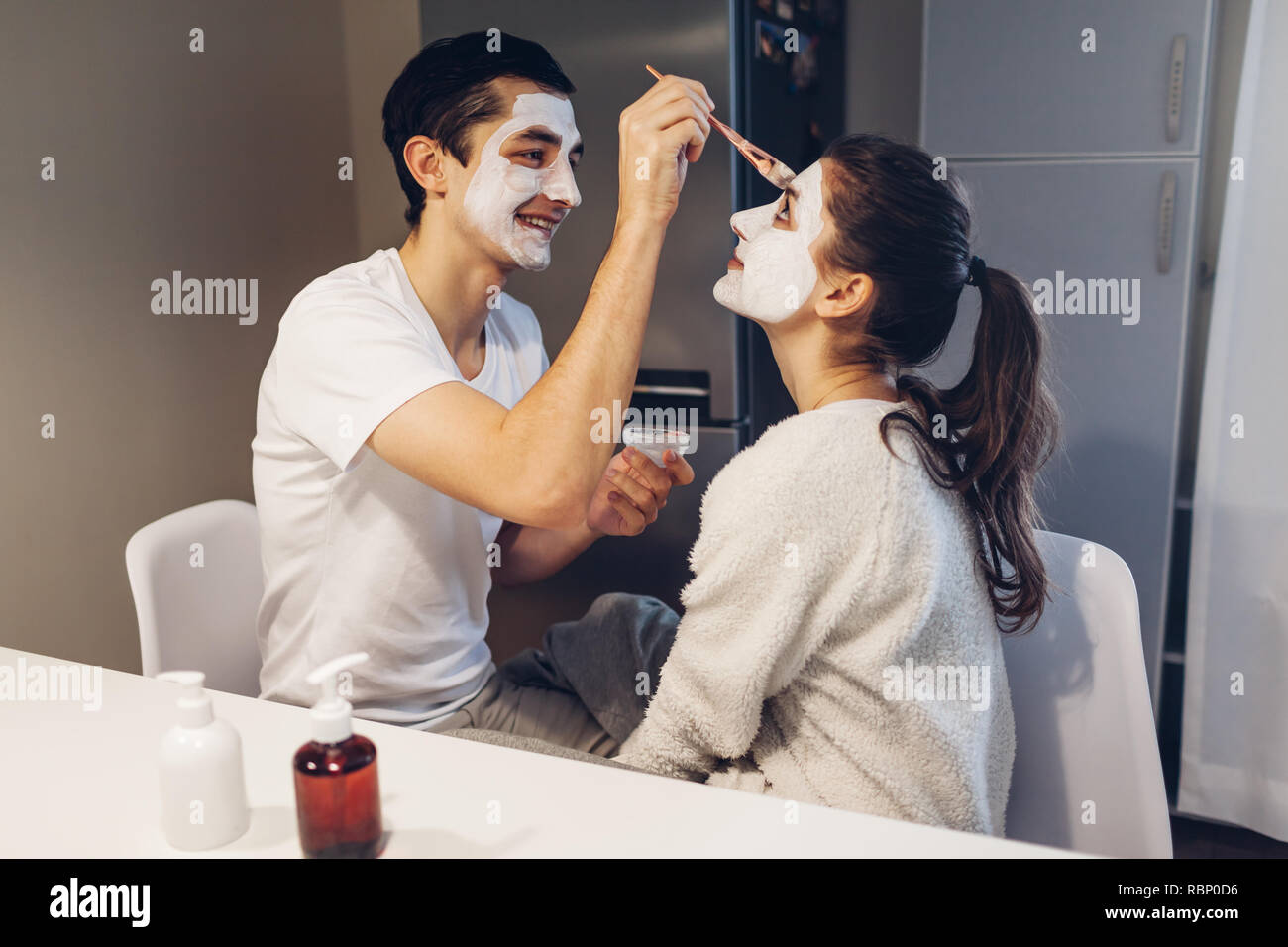 Mann Anwendung Clay Mask auf das Gesicht seiner Freundin. Junge Liebespaar  die Pflege der Haut auf Küche zu Hause Stockfotografie - Alamy