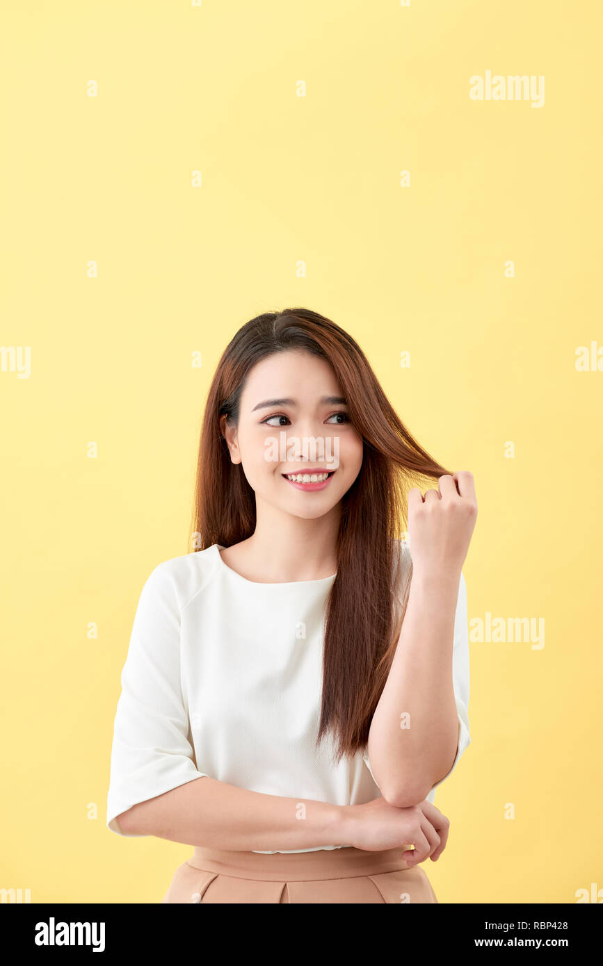 Asiatische Frau lächelnd mit Vertiefung lange Haare schwarz Augen auf gelben Hintergrund süßes nettes Mädchen Gesicht Vintage Style schöne asiatische Mädchen orientalische Mädchen schwarz h Stockfoto