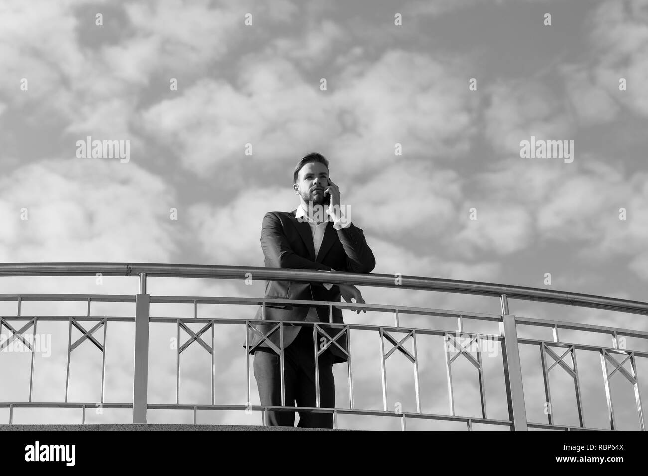 Chef sprechen auf Handy am blauen Himmel. Geschäftsmann mit Smartphone. Mann in Anzug an sonnigen Außenpool. Das moderne Leben und Business Lifestyle. Business Kommunikation, neue Technologie und sms. Stockfoto