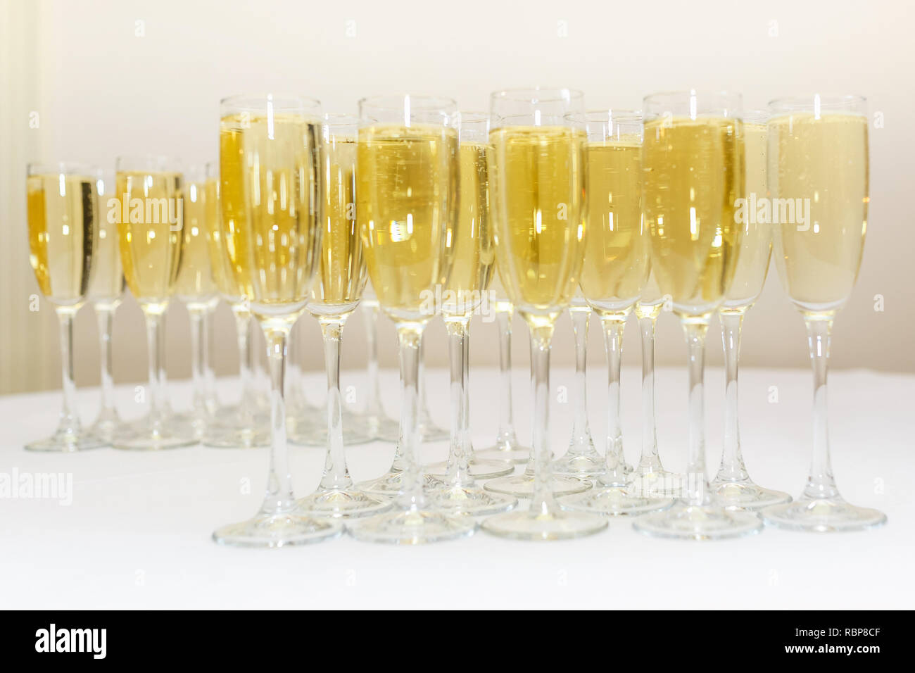 Menge unscharfer Gläser mit Champagner auf der Rezeption Partei Tabelle auf hellen Hintergrund Stockfoto