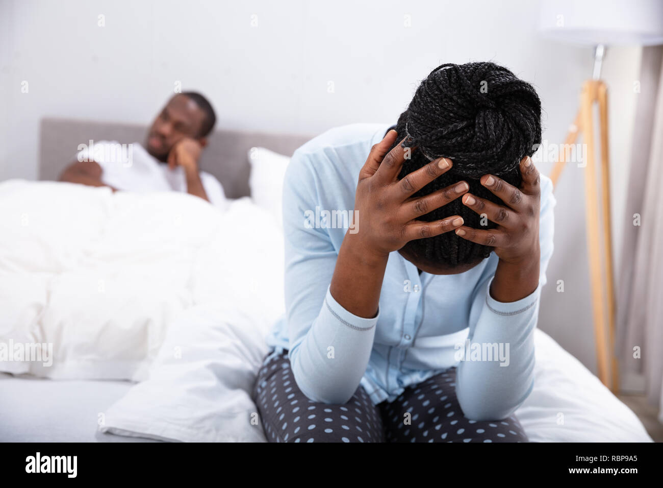 Nahaufnahme der traurigen Frau sitzt auf dem Bett vor ihrem Mann Stockfoto