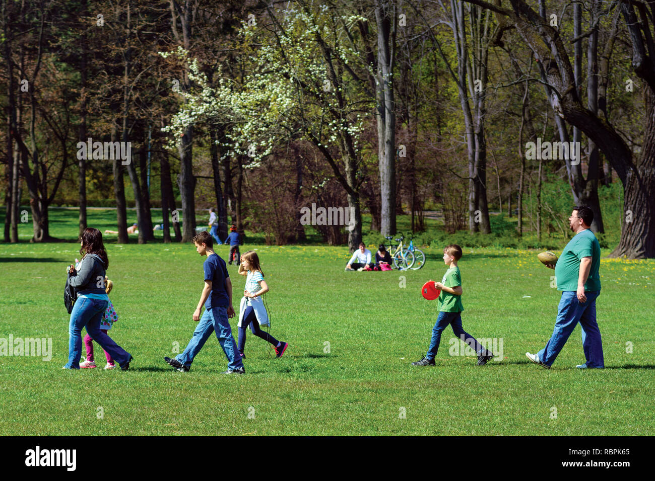Familie Gruppe entlang der grünen Wiese im Stadtpark, Rugby Ball und Frisbee Stockfoto