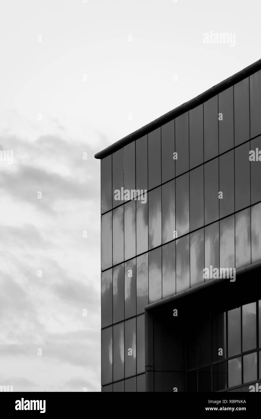 Modernes Gebäude mit vorgehängten Glasfassade mit bewölktem Himmel Reflexionen und Hintergrund, Schwarz und Weiß Stockfoto