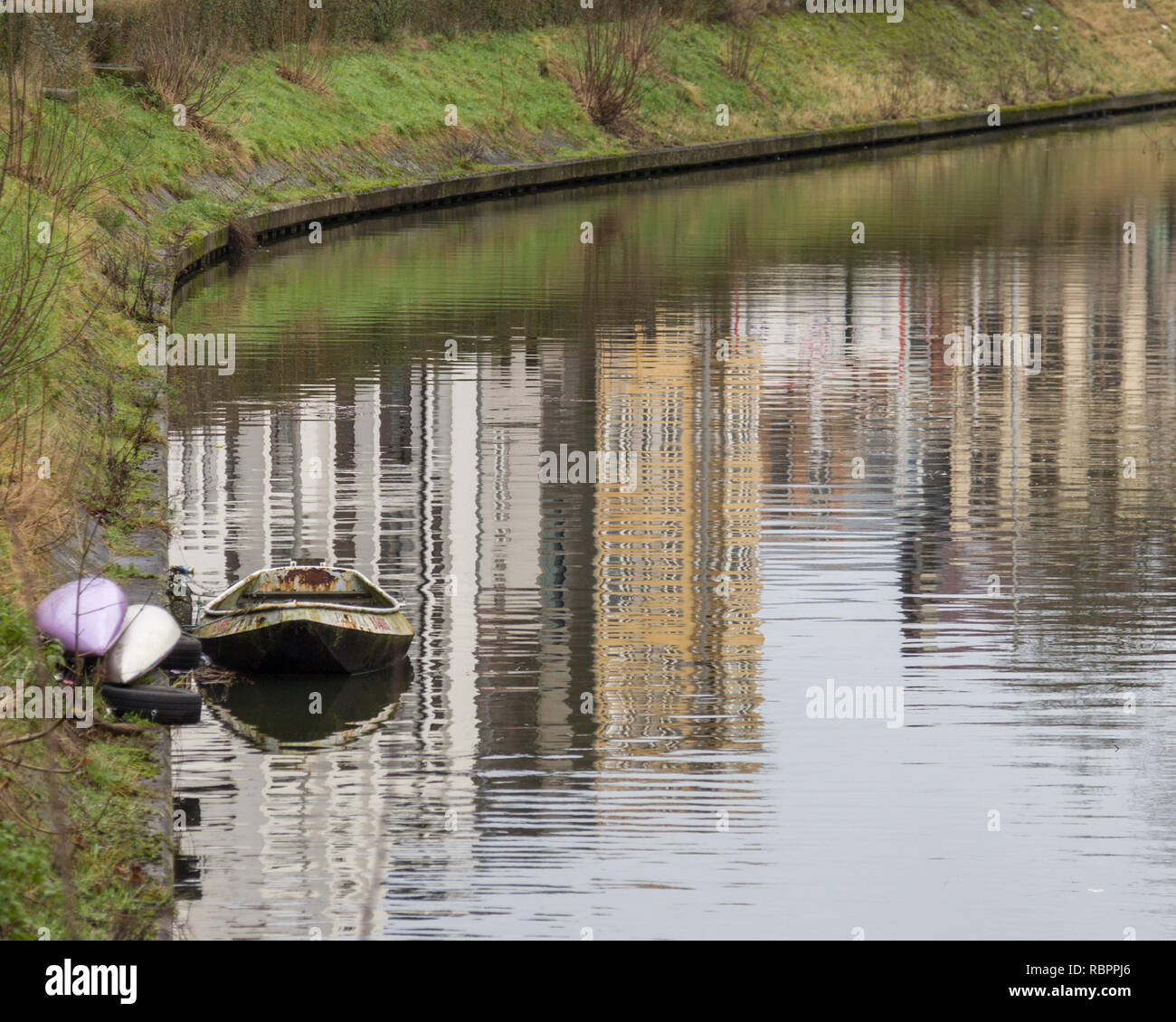 Ein kleines Boot ist an der Seite eines Kanals in Gent, Belgien günstig neben zwei Kajaks Stockfoto