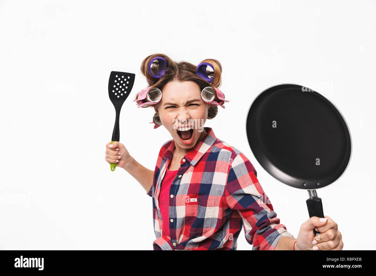 Wütend Hausfrau mit Lockenwicklern im Haar, die auf weißem Hintergrund, die Pfanne Stockfoto