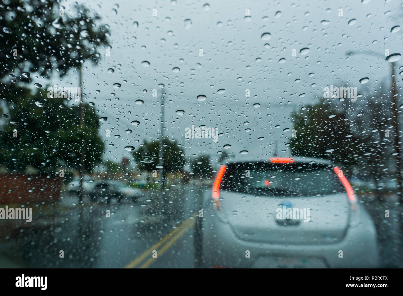 Regentropfen auf der Windschutzscheibe während der Fahrt an einem regnerischen Tag; Kalifornien Stockfoto
