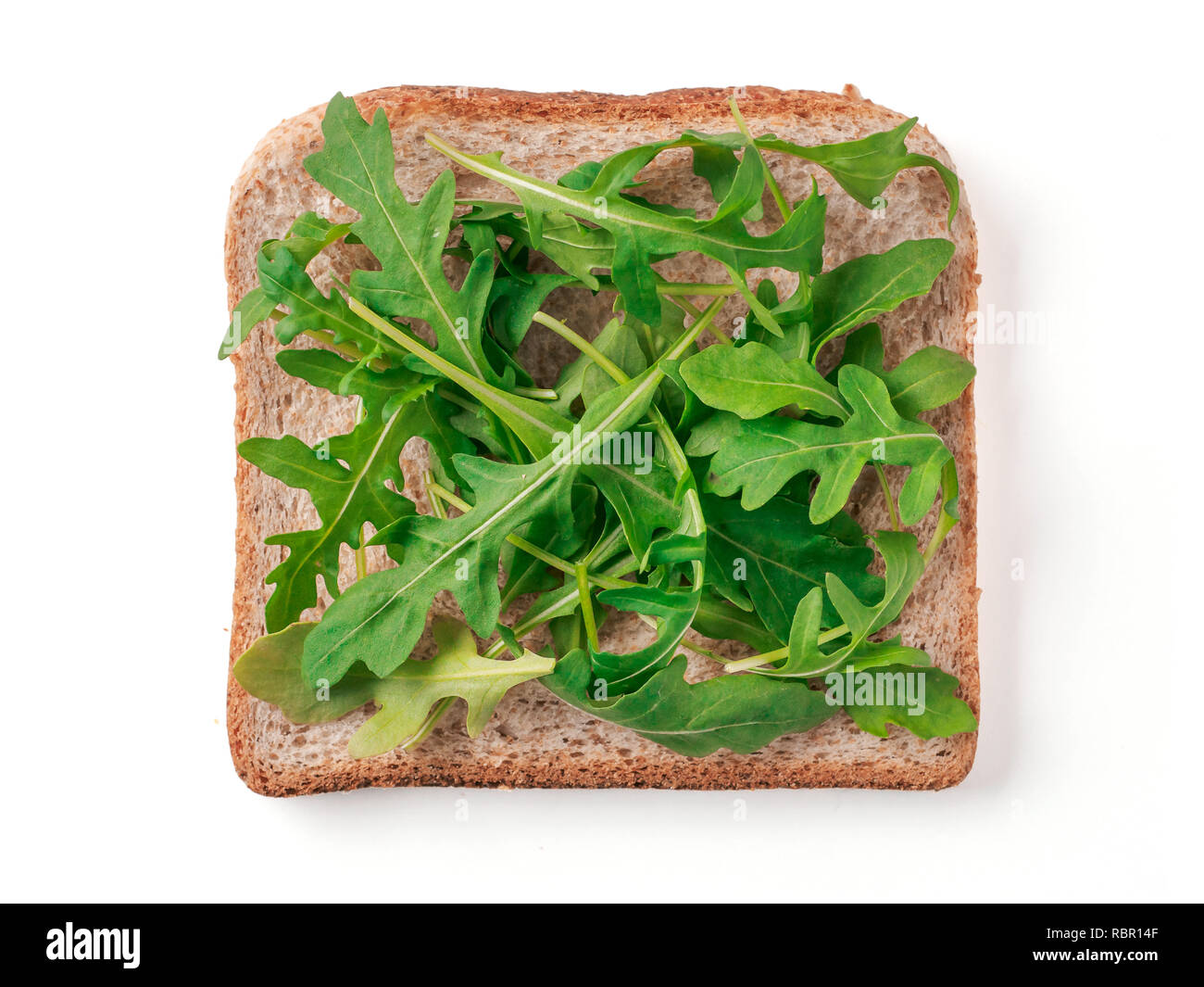 Brot Scheibe mit Rucola Blätter auf weißen, Beschneidungspfade isoliert. Scheibe Mehrkornbrot quadratische Form mit grünen Rucola Blätter für Toast. Bild von einer Scheibe Vollkornbrot, Ansicht von oben oder flach. Stockfoto