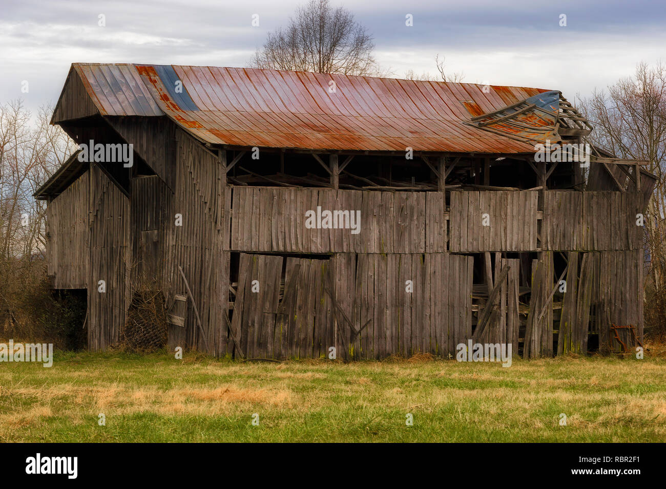 Einer alten zerfallenden Scheune sitzt unter bewölktem Himmel im ländlichen Tennessee Stockfoto