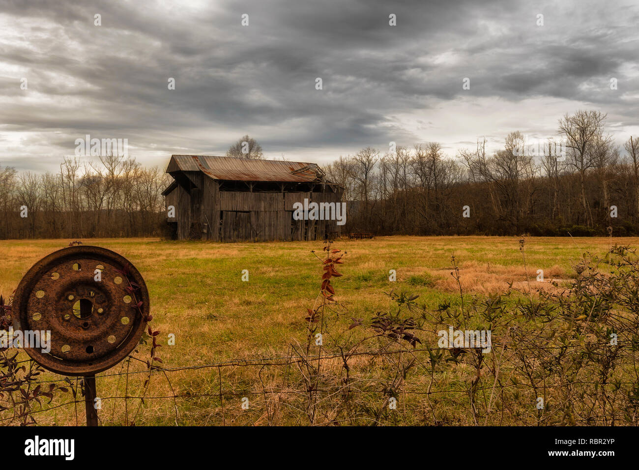 Einer alten zerfallenden Scheune sitzt unter bewölktem Himmel im ländlichen Tennessee Stockfoto