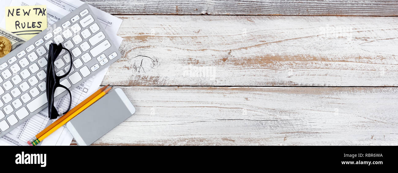 Einkommensteuer Formulare mit der neuen Regel Änderungen plus traditionelle und cyber Währung auf Weiß rustikal Schreibtisch Stockfoto