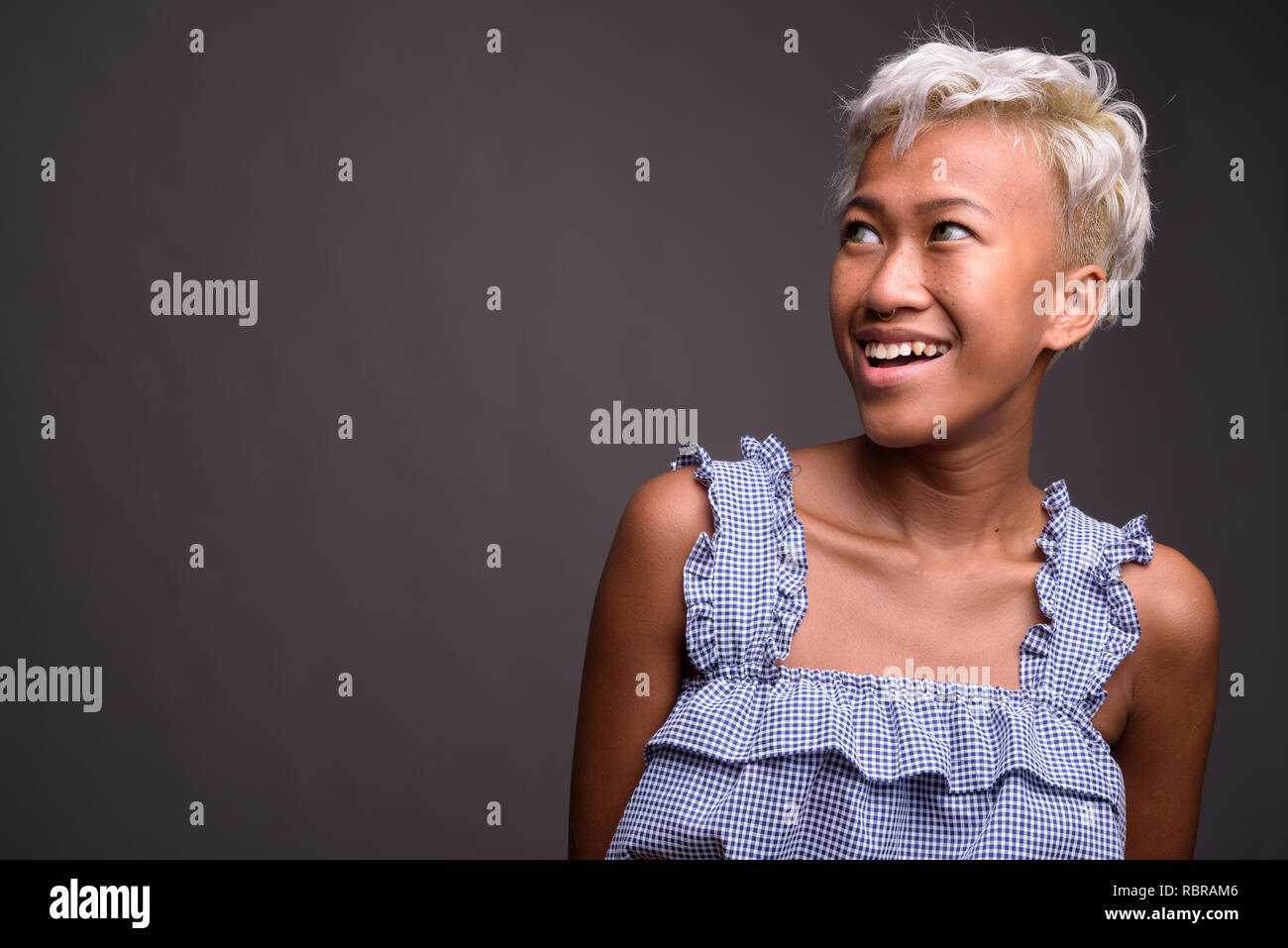 Junge schöne Frau mit kurzen Haaren lächeln und denken Stockfoto