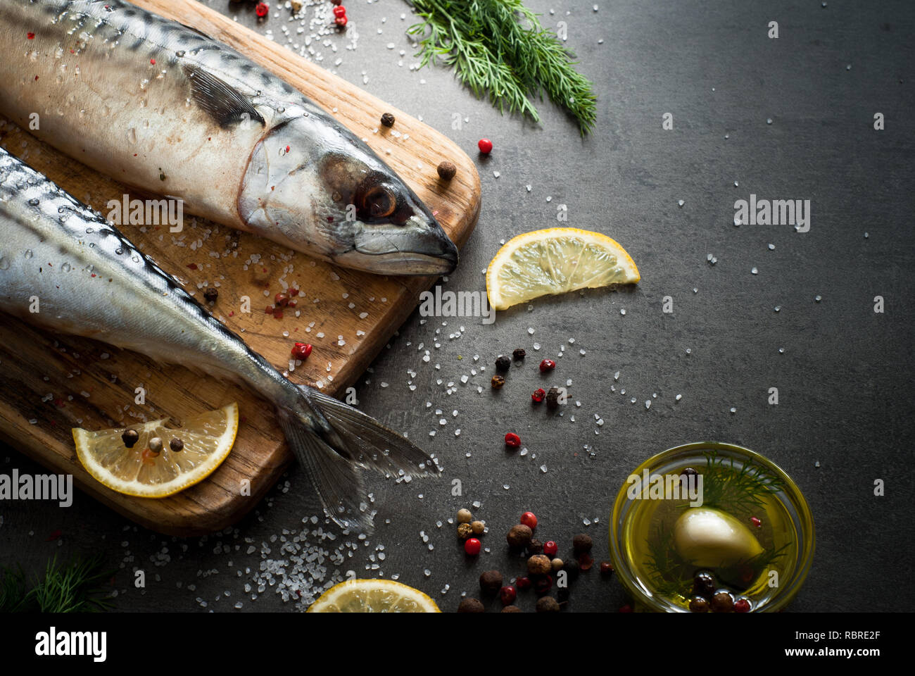 Frischer Fisch. Rohe Makrele mit Salz, Zitrone und Gewürzen auf einem dunklen Hintergrund. Stockfoto