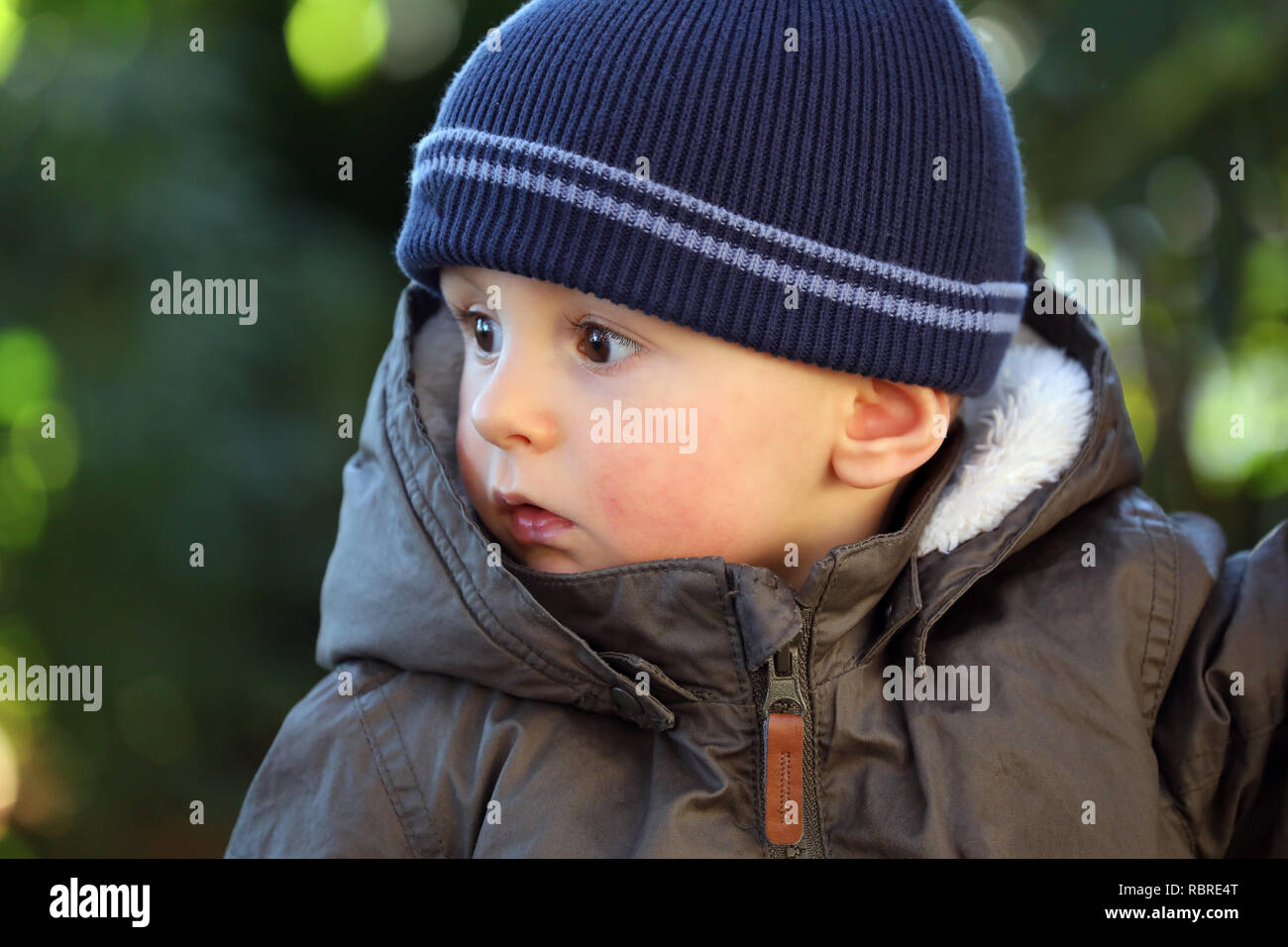 Close Up Portrait von Cute Baby Boy trägt einen blauen und grünen Hut Stricken Winter Winter Parka Stockfoto