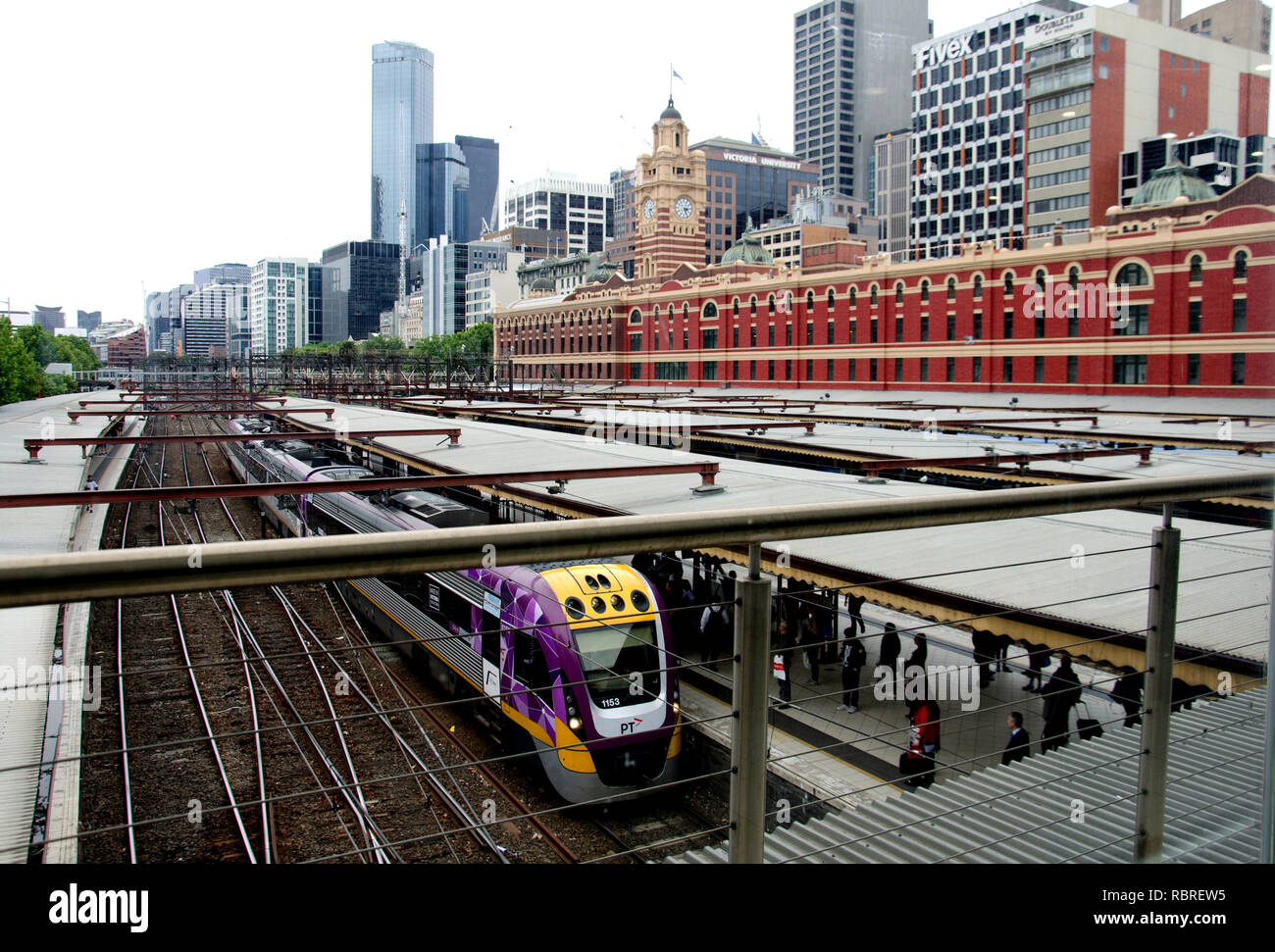 Ein bunt bemalten Zug stoppt bei einem Plattform von Melbourne Flinders Street Station Stockfoto