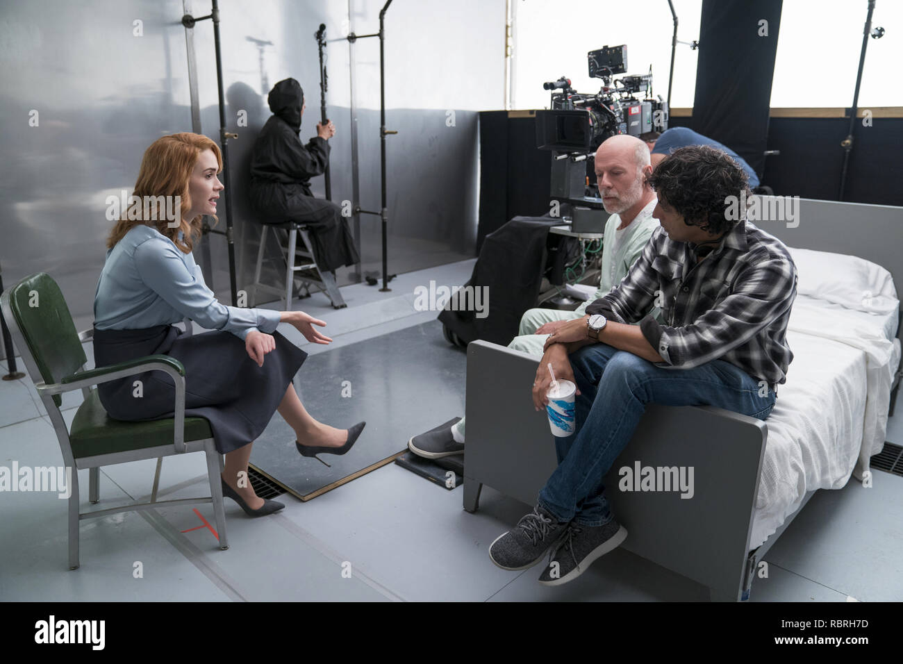 (Von links) Sarah Paulson, wer spielt Dr. Ellie Heften, Bruce Willis, wer spielt David Dunn/der Aufseher und Schriftsteller und Regisseur M.Night Shyamalan auf dem Set von "Glas." Foto: Universal Pictures/Hollywood Archiv Stockfoto