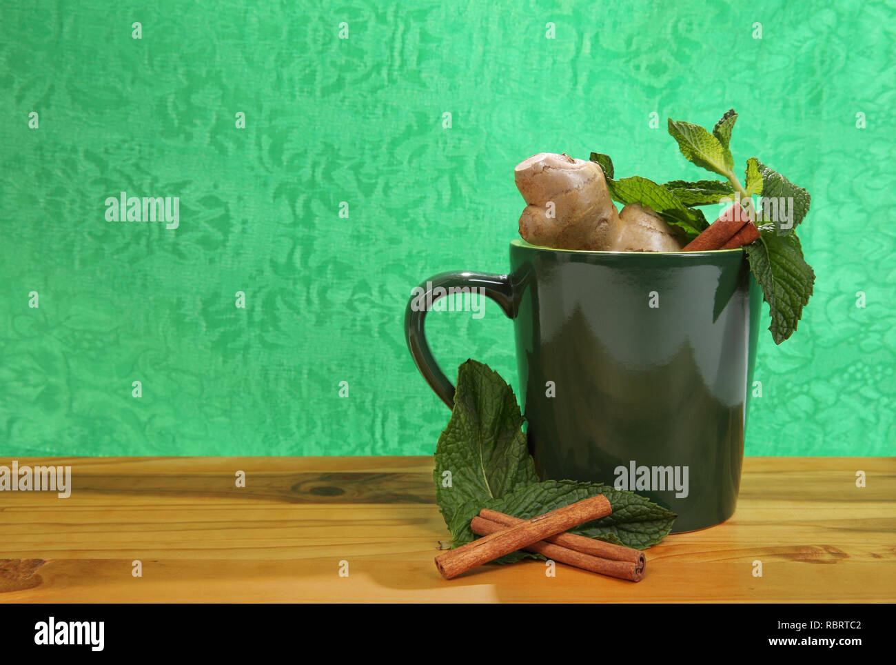 Grüne Tasse mit natürliche pflanzliche Inhaltsstoffe auf grünem Hintergrund Stockfoto