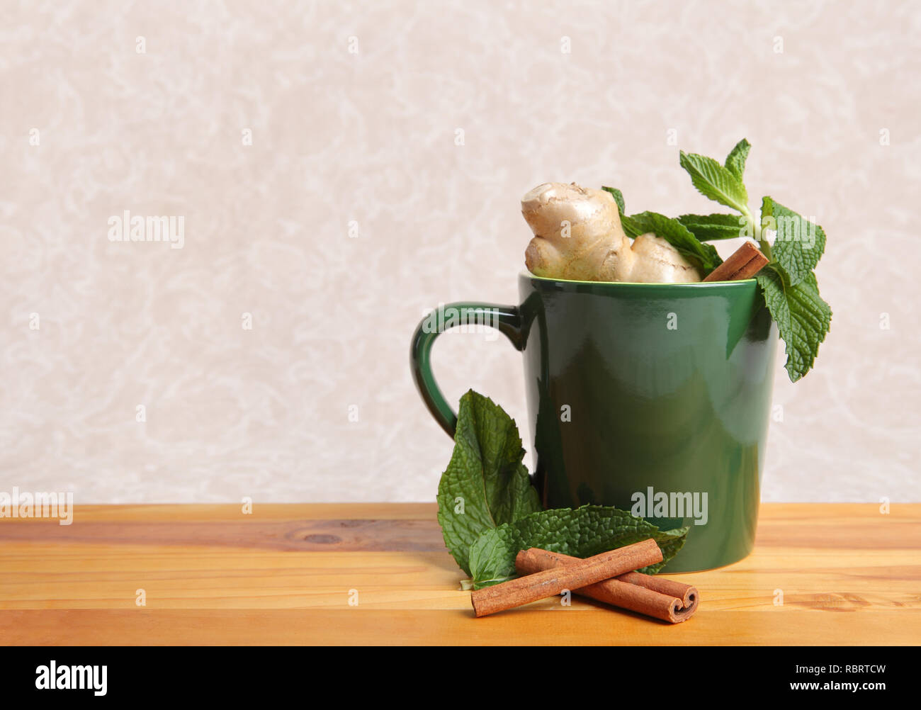 Grüne Tasse mit natürlichen pflanzlichen Inhaltsstoffe auf tan Hintergrund Stockfoto