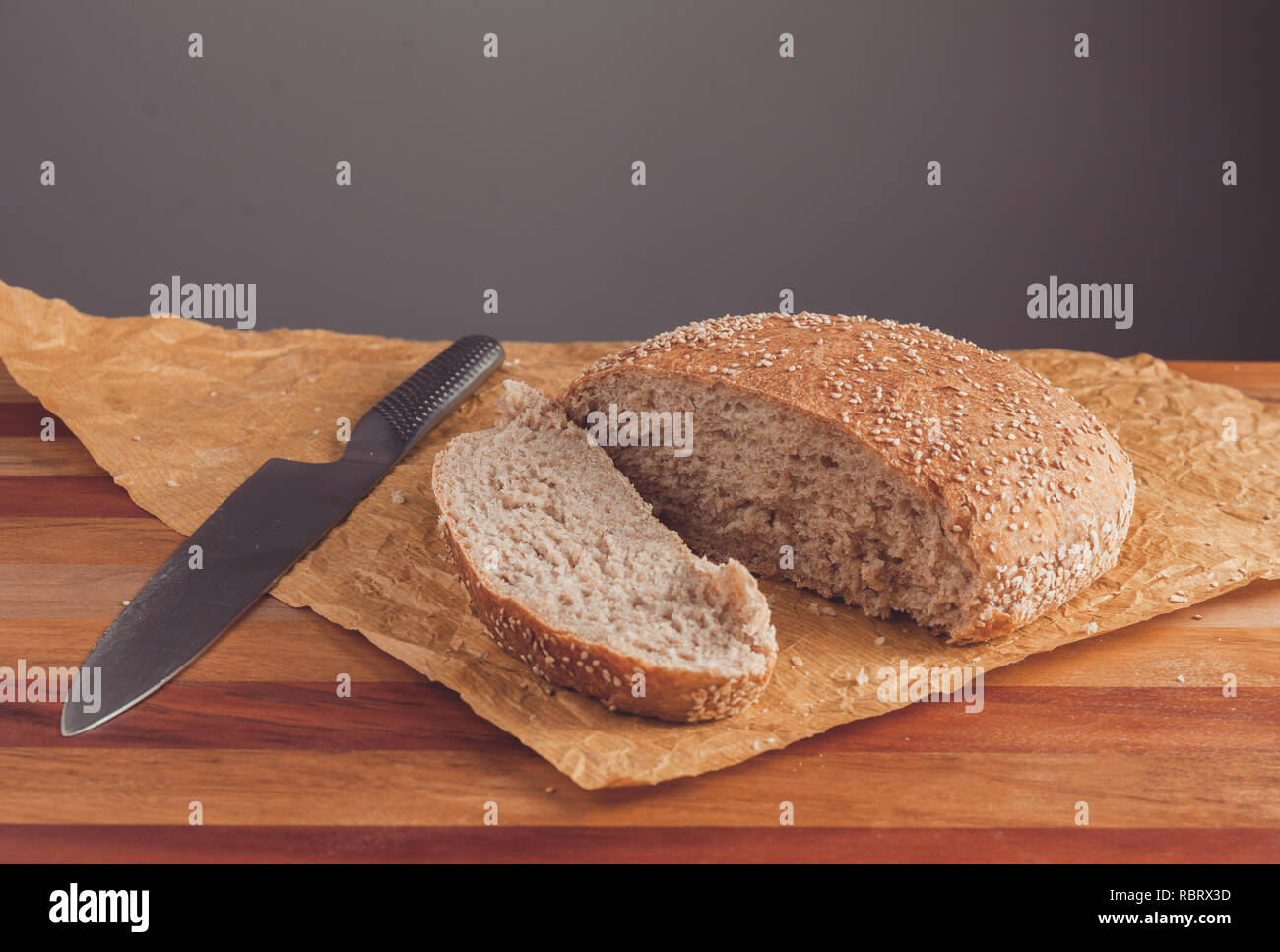 Frisch gebackenen Laib Vollkornbrot mit Kleie, auf Backpapier. Von Messer in Scheiben geschnitten Stockfoto