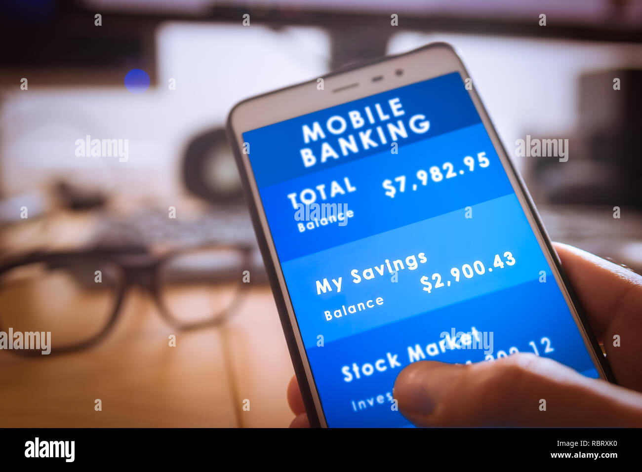 Männliche hand holdding ein Smartphone mit Mobile Banking auf dem Bildschirm mit unscharfen Büro Hintergrund Stockfoto