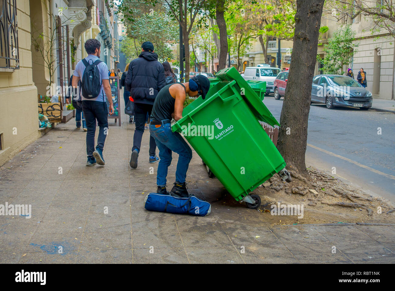 SANTIAGO, CHILE - 14. SEPTEMBER 2018: Im freien Blick auf unbekannter Mann auf der Suche nach Nahrung in einer grünen garvage Sammler auf der Straße in der Stadt von Santiago entfernt Stockfoto