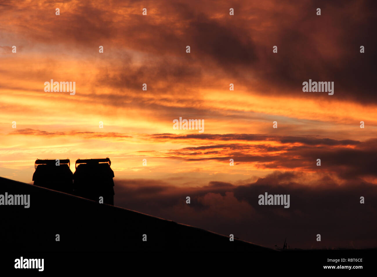 Dächer und Kamine bei Sonnenuntergang mit Wolken und Smog in Rom, Italien Stockfoto