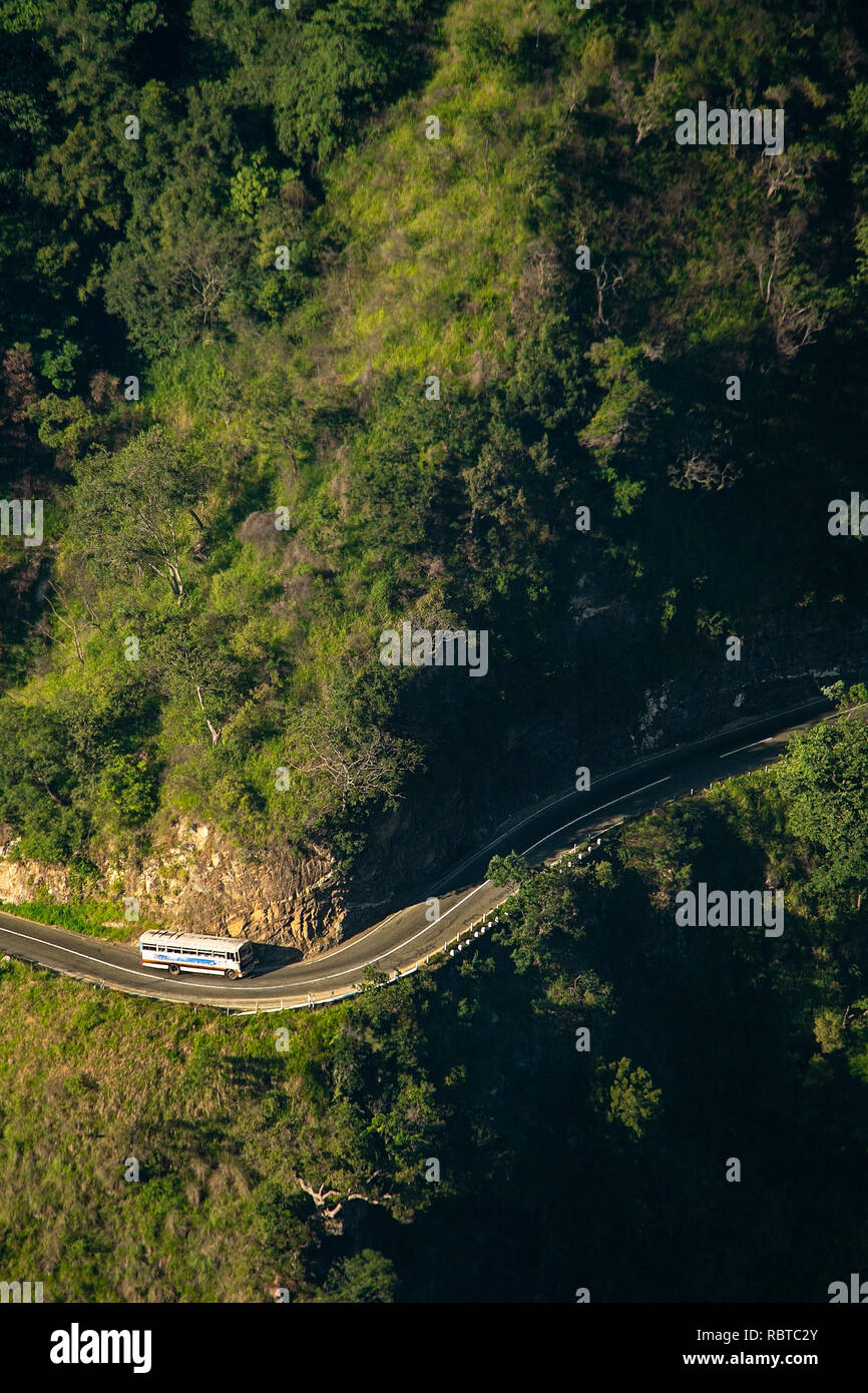 Einen lokalen öffentlichen Nahverkehrs bus windet sich um einen ansteigenden Hang bendy Straße, gesehen von oben. Stockfoto