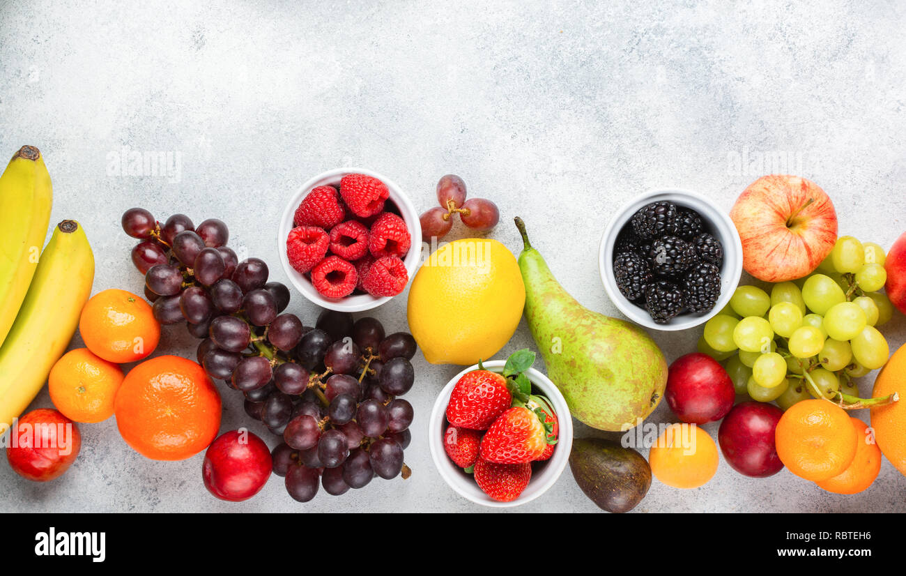 Blick von oben auf die köstlichen Früchte Himbeeren, Orangen, Pflaumen Äpfel Birnen Trauben Heidelbeeren Bananen Erdbeeren auf weißem Tabelle, Ansicht von oben, kopieren Raum Stockfoto