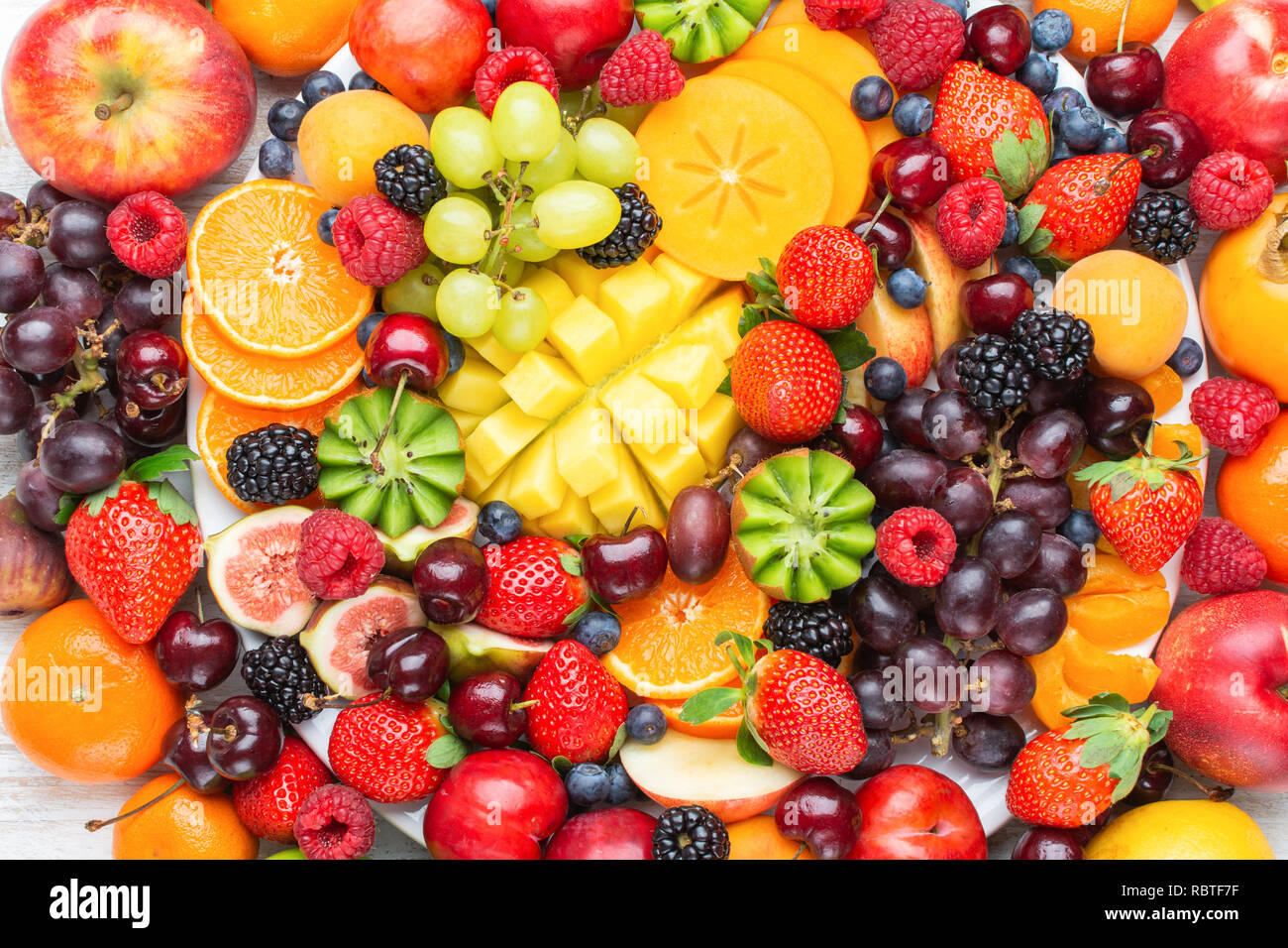 Gesunde Obstteller Hintergrund Pflaumen Erdbeeren Himbeeren, Orangen, Äpfel, Kiwis, Weintrauben, Heidelbeeren mango Kaki, Ansicht von oben, Stockfoto