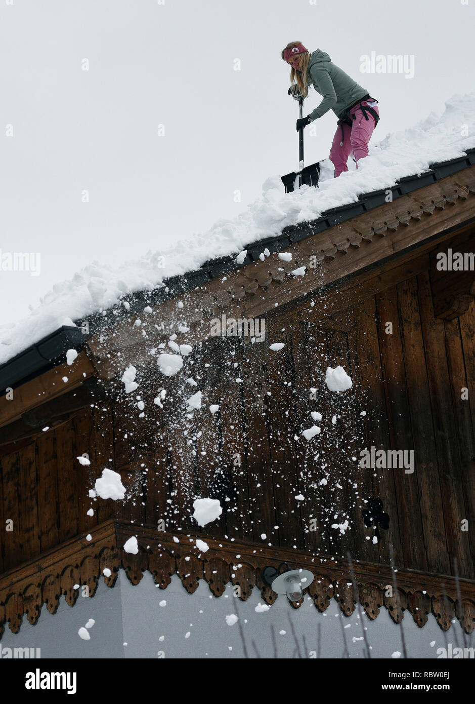 Garmisch Partenkirchen, Deutschland. 12 Jan, 2019. Eine Frau befreit Ihr Dach vom Schnee laden. Die starken Schneefälle der vergangenen Tage weiterhin den Einsatzkräften in Atem im südlichen Bayern und Neuschnee zu halten ist schon näher. Quelle: Angelika Warmuth/dpa/Alamy leben Nachrichten Stockfoto