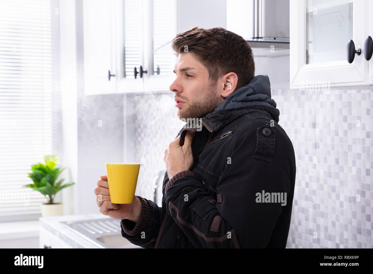 Mann mit Schal um den Hals Leiden unter Kälte Holding Tasse Kaffee Stockfoto