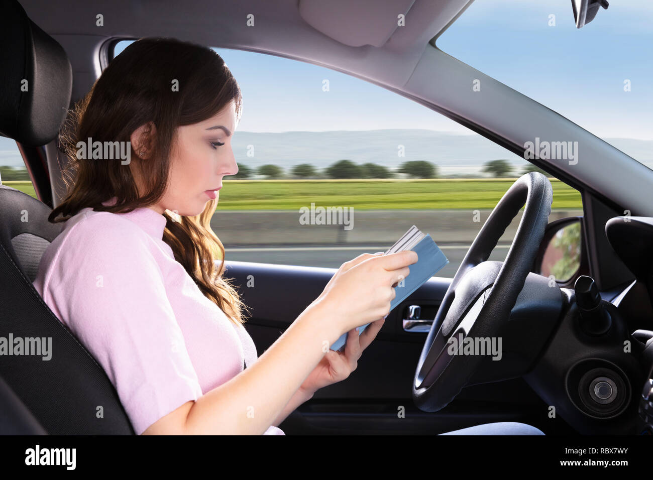 Seitenansicht einer schönen Frau mit Buch beim Fahren Auto Stockfoto